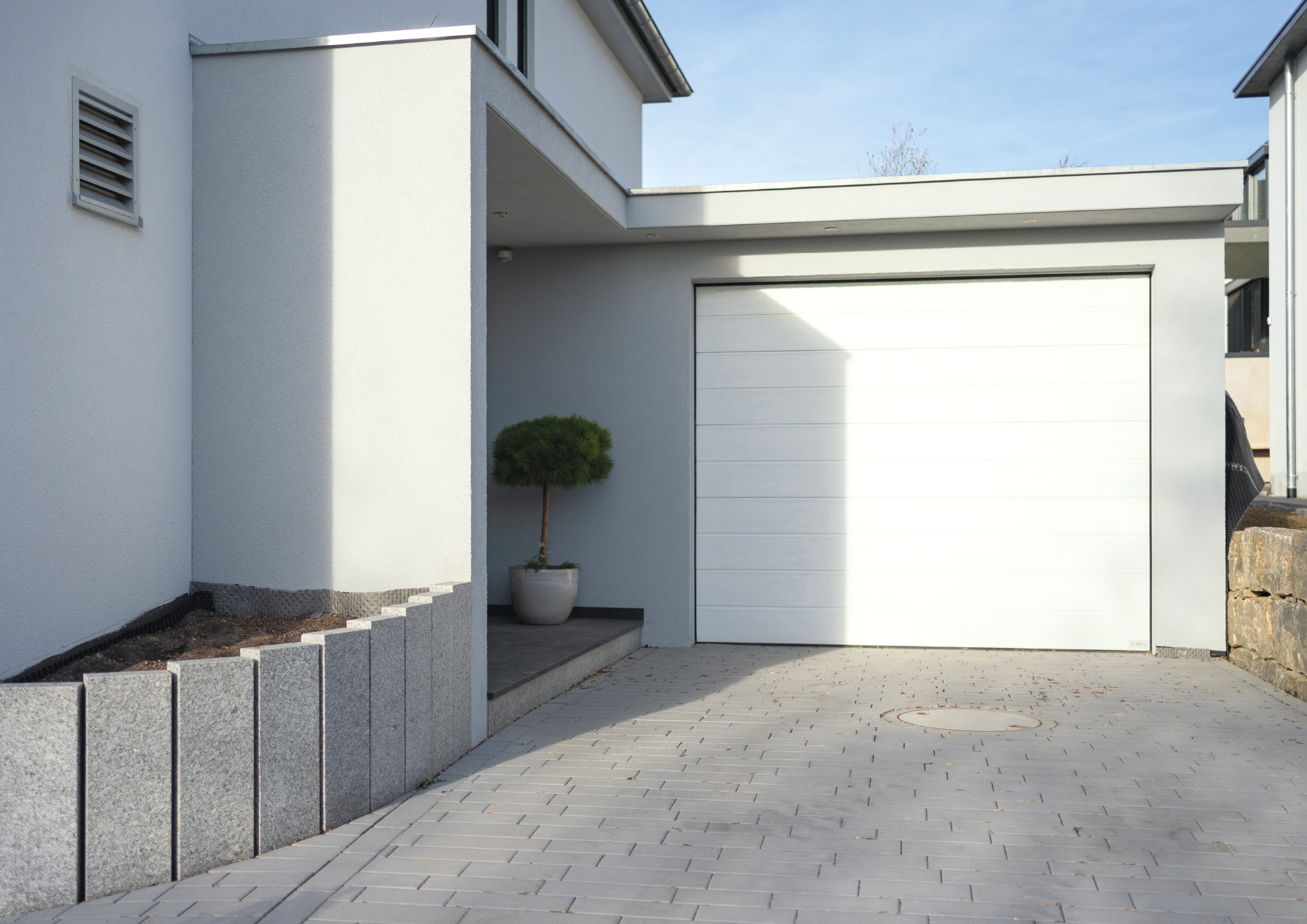 Garage mit Eingangsüberdachung und Carport mit Stützwänden