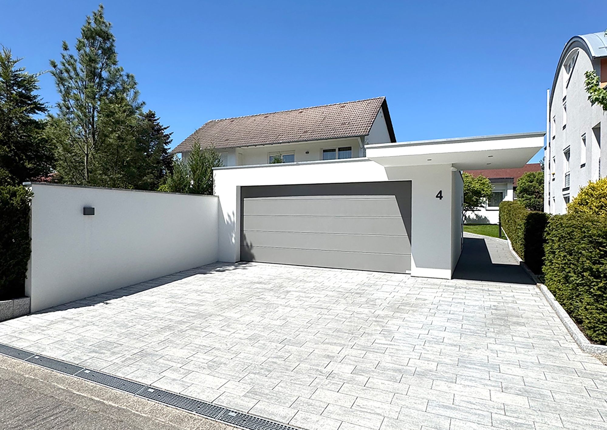 Große Garage mit Stützmauer und Eingangsüberdachung